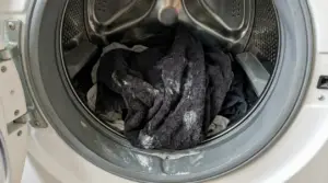 Panni bagnati e induriti con residui di detersivo all'interno di una lavatrice aperta