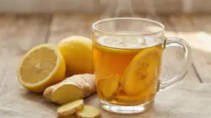 Tisana calda con fette di limone e zenzero fresco su tavolo di legno